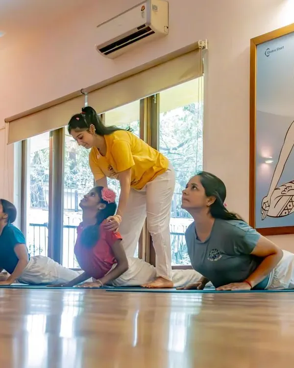 An instructor offers gentle guidance during Cobra Pose, ensuring young practitioners learn with proper form. Our hands-on approach helps children build a strong and safe foundation in their asana practice.