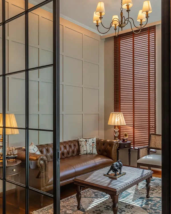 For this office at One Place Lodha, I used glass partitions to create separation without sacrificing the open, airy feel. The view into the lounge area shows a classic leather Chesterfield sofa, which adds a touch of timeless English style.