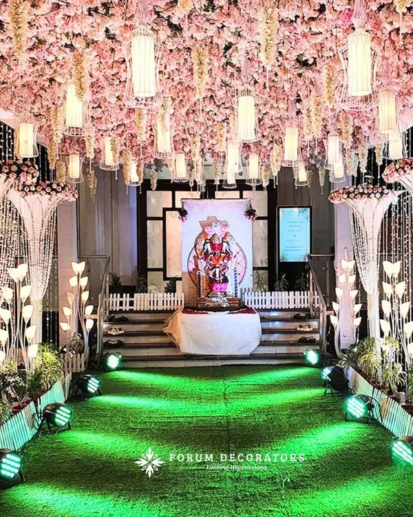 This is what I mean by a fairytale entrance. I used a dense ceiling of pink cherry blossoms and hanging white wisteria, interspersed with glowing lanterns, to create an immersive floral tunnel. The crystal bead curtains and spotlighting on the green turf walkway guide you towards the main event, making your first steps into the celebration truly magical.