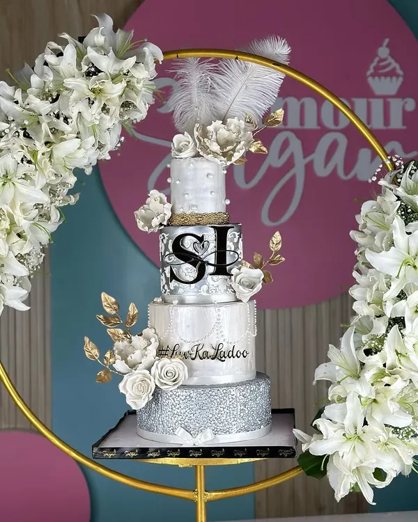 A masterpiece for a love that shines. This silver and pearl-themed wedding cake, framed by a floral hoop, combines intricate textures, delicate sugar flowers, and shimmering details for a look of timeless elegance.