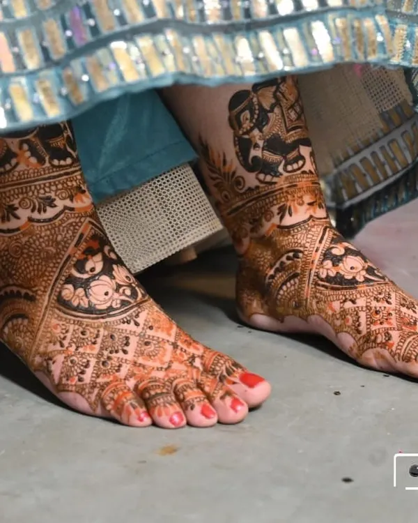 A detailed view of bridal foot mehandi, featuring traditional motifs that match the bride's overall look.