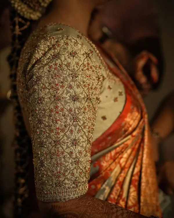 A detailed close-up of a fully embroidered blouse sleeve. The intricate jaal pattern is created with dense beadwork and thread, demonstrating the level of precision in my handwork for bridal couture.