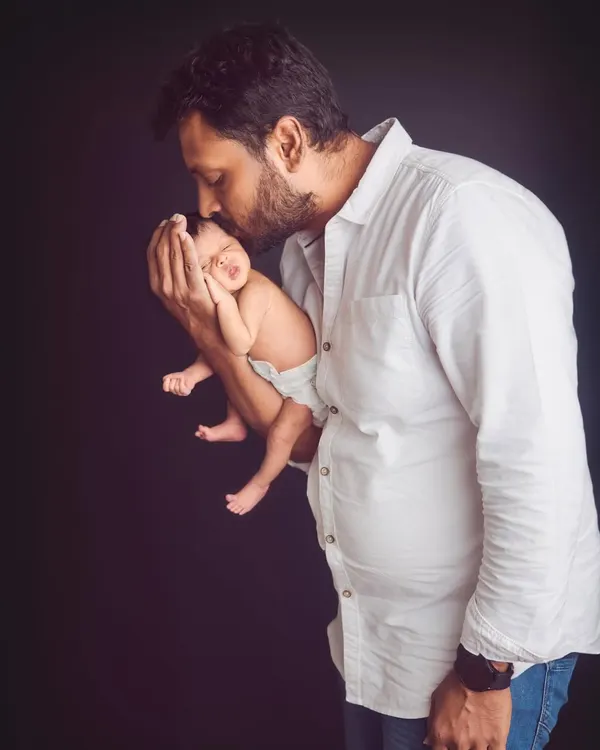 A father's gentle kiss for his newborn. This powerful image captures the profound bond between a dad and his baby in a simple, classic portrait.