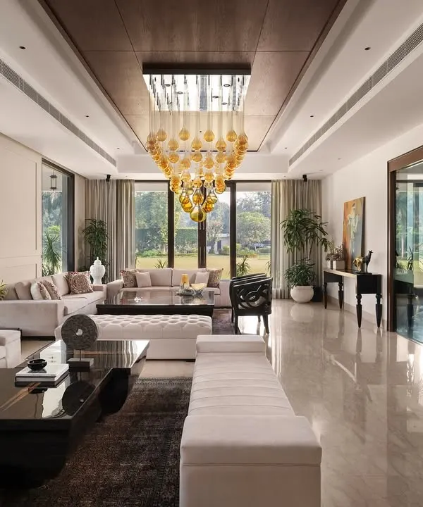 The drawing room at Mehalin Farm, featuring expansive glazing for abundant natural light. Muted wall mouldings and a statement chandelier introduce a neo-classical elegance to the spacious interior.
