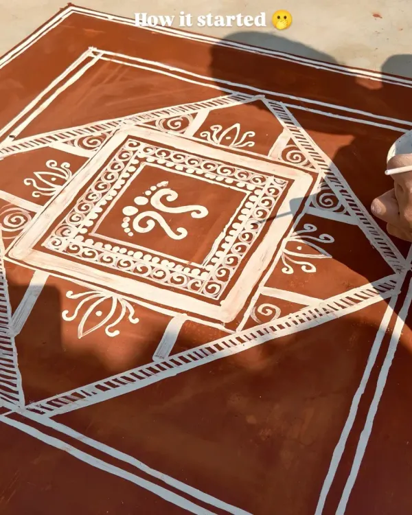 This image shows the process of creating a Mandana, a traditional floor painting from Rajasthan. Here, I am drawing the central motif of Goddess Lakshmi's footprints, a symbol of prosperity, using a cloth dipped in white paste.