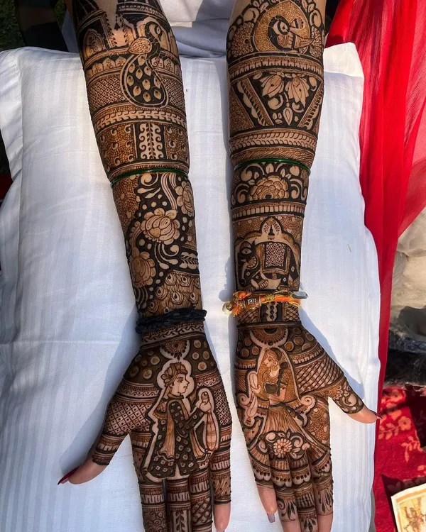 A complete bridal mehndi telling a love story. This design features detailed portraits of the bride and groom, surrounded by traditional motifs and patterns that extend up the arm, making it a true centerpiece for the wedding day.