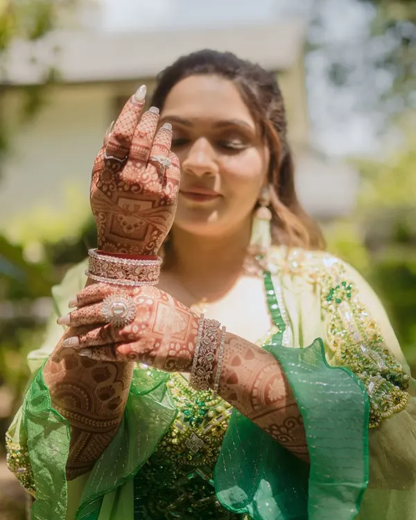 A close up of the bride admiring her intricate mehndi design. We focus on capturing the artistry of the henna and the bride's happy anticipation.