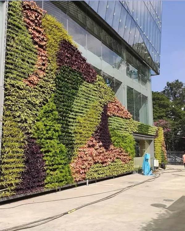 A massive vertical garden covering the facade of a multi-story commercial building, designed with waves of different plant textures and colors for a dynamic effect.