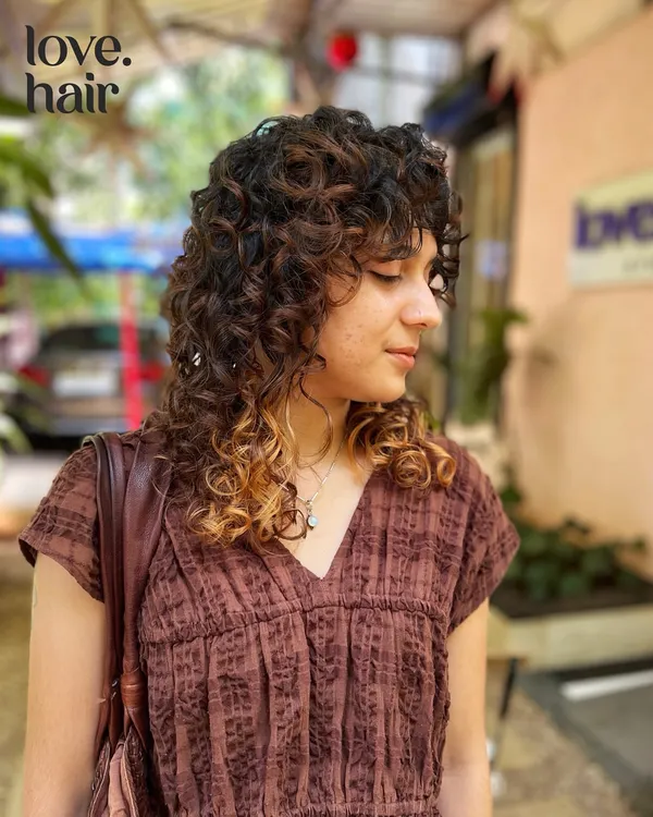 A curly shag with bangs is always a vibe. This cut adds tons of texture and shape, with subtle highlights at the tips to make the layers pop.