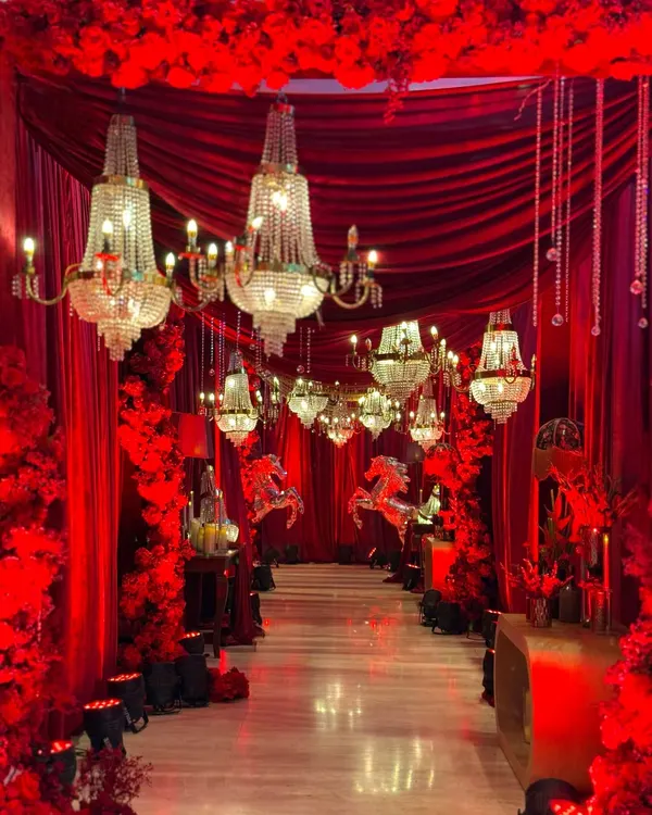 A breathtaking entrance designed to feel like stepping into a dream. We layered rich red velvet drapes with dozens of sparkling crystal chandeliers to create a passage of pure opulence for a truly grand Sangeet celebration.