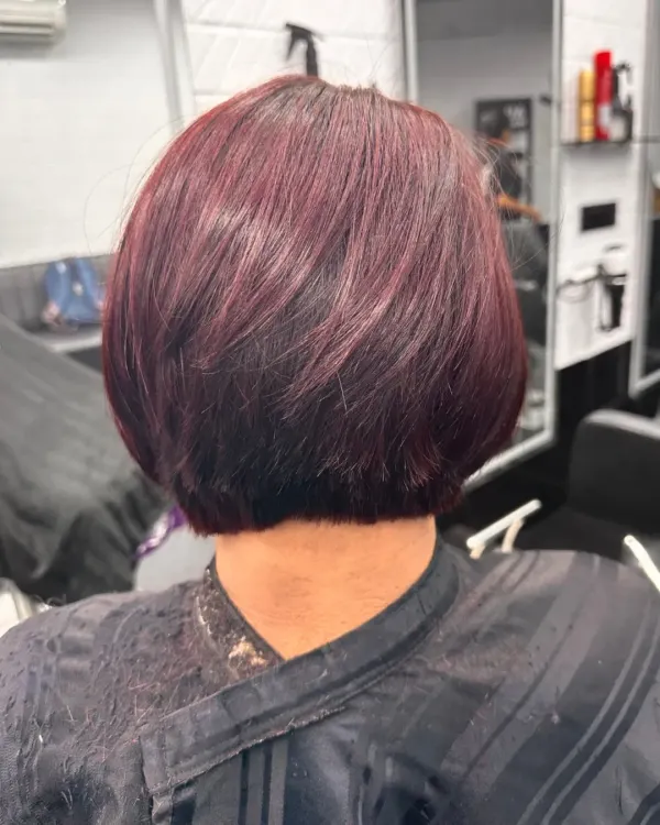A perfect example of a classic bob haircut. This short, sharp style is given a modern twist with a bold burgundy color, creating a look that is both timeless and edgy.