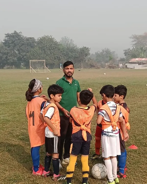 A coach gives instructions to our U8 team during a huddle at a friendly match. We focus on clear communication and building confidence from a young age.