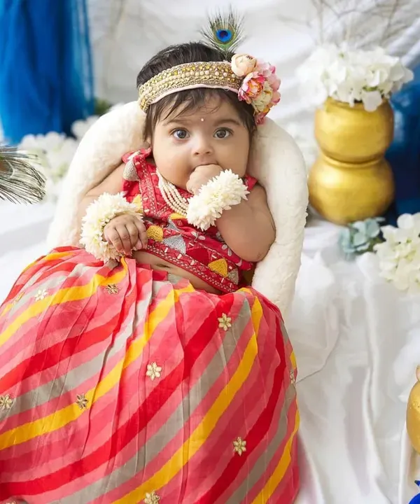 Our little Radha celebrating Janmashtami. The colorful lehenga, peacock feathers, and pots of 'butter' create a beautiful and traditional scene for the festival.