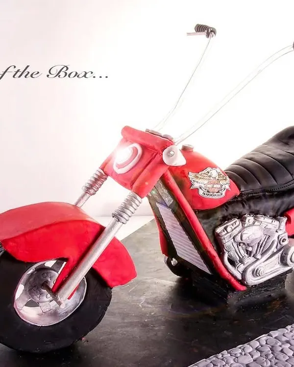 A stunning, life-like 3D Harley Davidson motorcycle cake, sculpted with incredible attention to detail, from the engine to the handlebars.