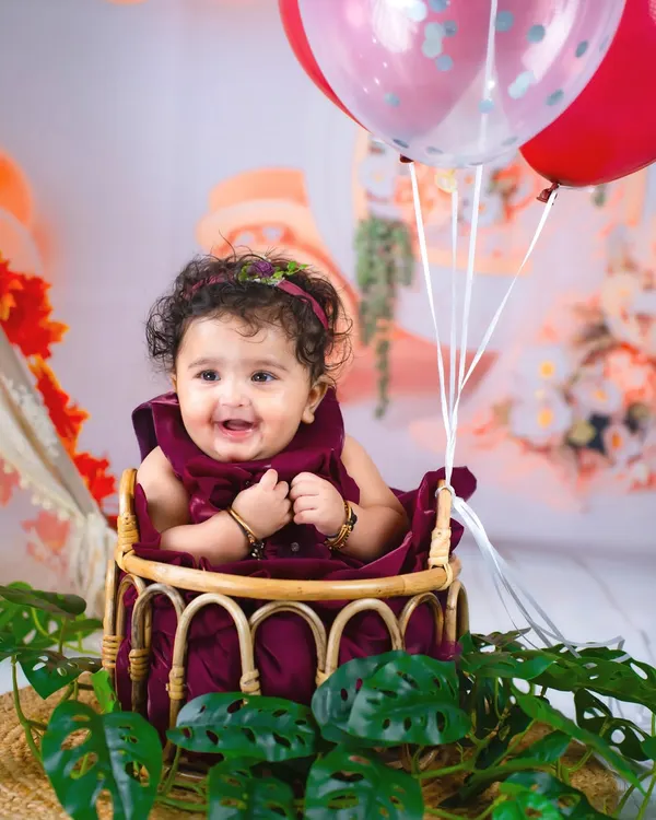 Six months of sweetness! This close-up shot captures the happy, gummy smile of a six-month-old during her half-birthday photoshoot, surrounded by balloons.
