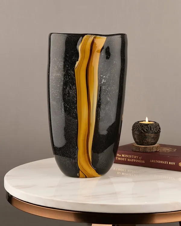 This handblown glass vase features a dramatic streak of gold running through a black, textured body. It's a subtle yet stunning piece that looks beautiful on its own or with a simple flower stem.