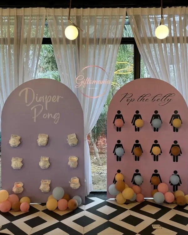 A full view of the baby shower game station, featuring 'Diaper Pong' and 'Pop the Belly' boards in a pastel color scheme. These games are always a huge hit with guests.