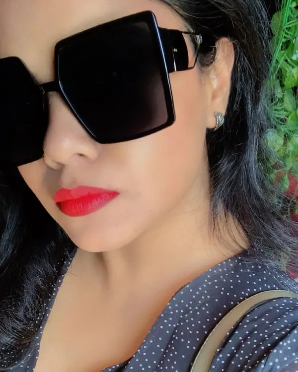 A bold red lip and oversized square sunglasses are a power combination. This close-up shows how accessories and makeup create a 'main character' vibe.