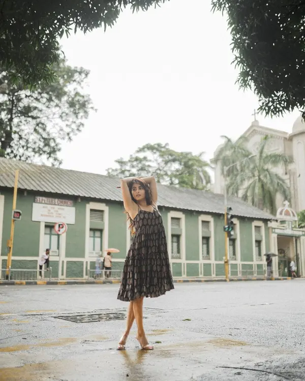 A full-length shot of a model on a quiet Mumbai street, using the urban architecture and overcast sky to create an atmospheric fashion photo.