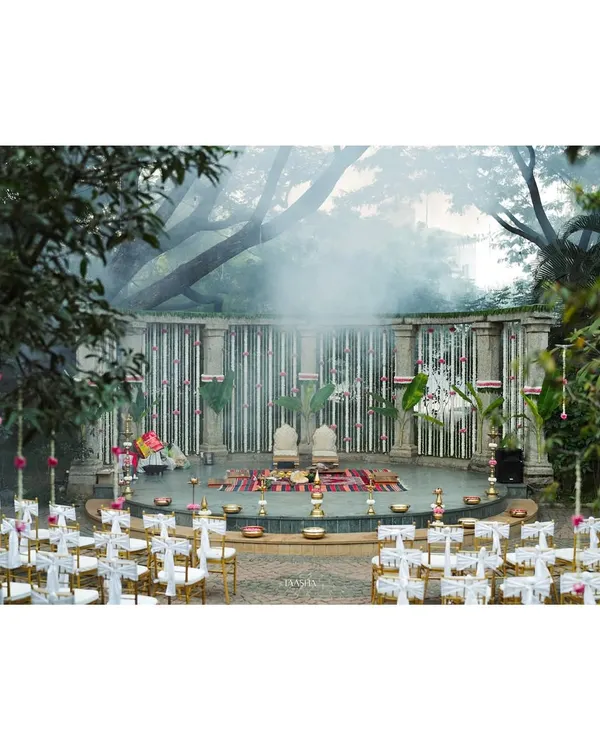 A wide view of the traditional wedding ceremony at Shankaraa Foundation, showing the seating arrangement facing the magnificent stone amphitheater mandap. The misty atmosphere adds a layer of mystique and romance to the sacred proceedings.