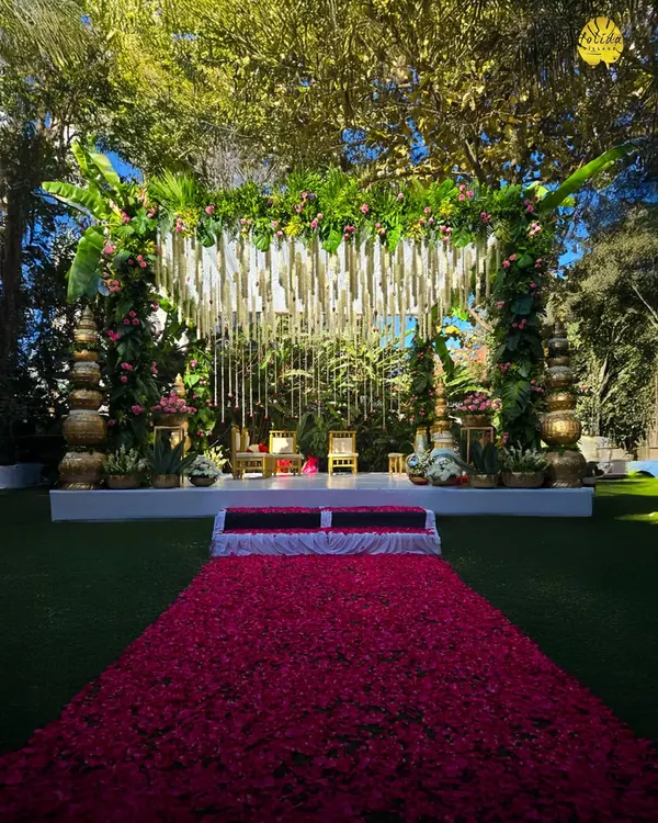 This grand wedding mandap, set against our lush greenery with a dramatic rose petal aisle, showcases how we create breathtaking focal points for your ceremony.
