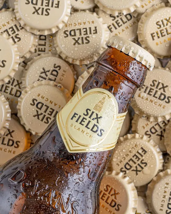 A refreshing shot for Six Fields beer, using a bed of bottle caps and water droplets to create a cool, textured image that makes you want to grab a cold one.