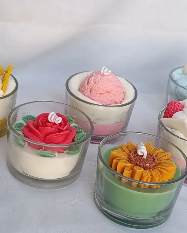 I offer a wide variety of dessert-themed candles. This image shows a collection including a mango dessert candle, a strawberry ice cream scoop, a cloud candle, a rose cake candle, and a sunflower candle.