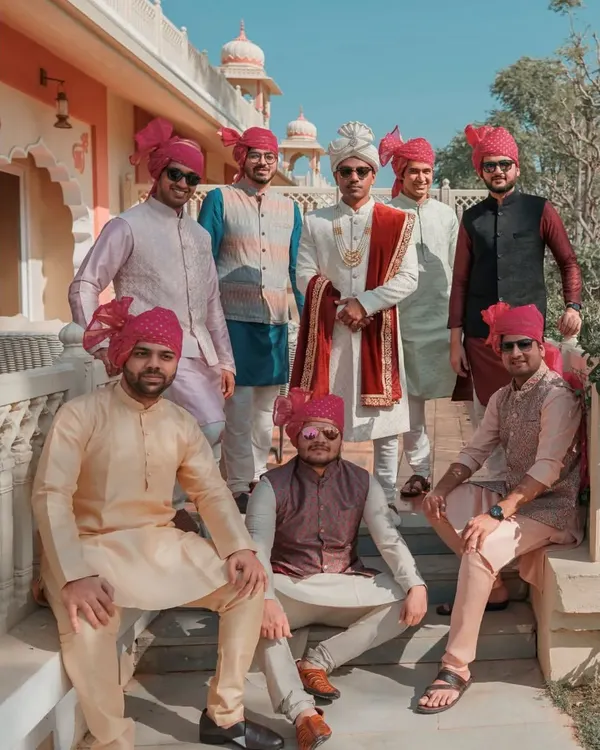 The groom and his groomsmen posing for a stylish group photo in their traditional Indian attire and vibrant pink turbans. A perfect shot of the groom's squad.
