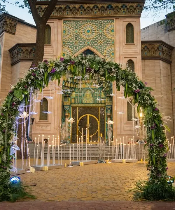 The entrance to this 25th-anniversary party was designed to be magical. A lush floral archway welcomed guests, leading them down a path lined with beautiful illuminated lotus flowers towards the magnificent venue.