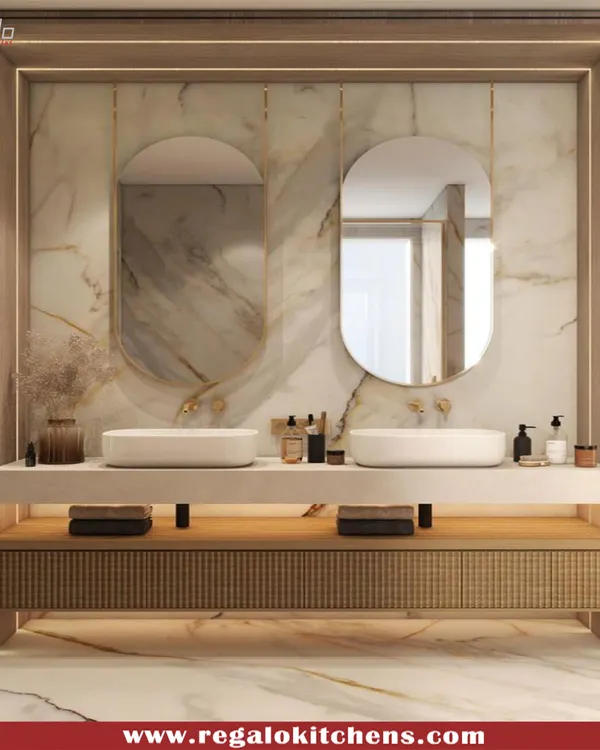 A stunning vanity design featuring a marble countertop, dual vessel sinks, and elegant oval mirrors. The reeded wood cabinetry and soft lighting create a spa-like atmosphere.