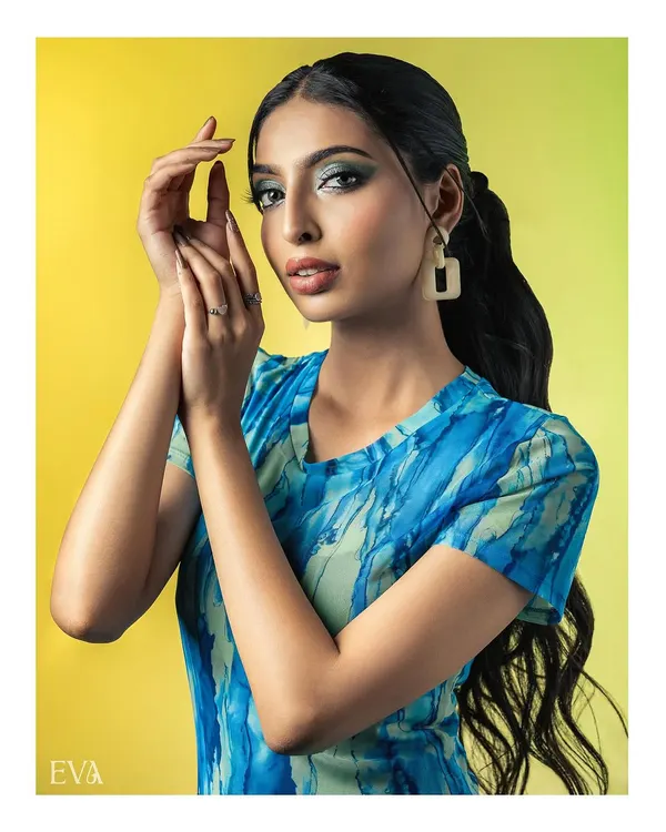A vibrant studio portrait featuring a model in a blue and green patterned dress against a bright yellow backdrop. Her confident pose and the bold color contrast create a fresh and modern fashion statement.