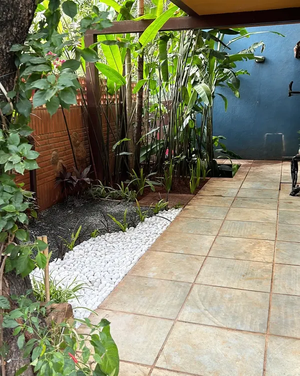 A welcoming entrance we designed for a villa in CV Raman Nagar. We used a combination of lush tropical plants, clean white pebbles, and natural stone tiles to create a pathway that feels both modern and serene, inviting you into a peaceful home.
