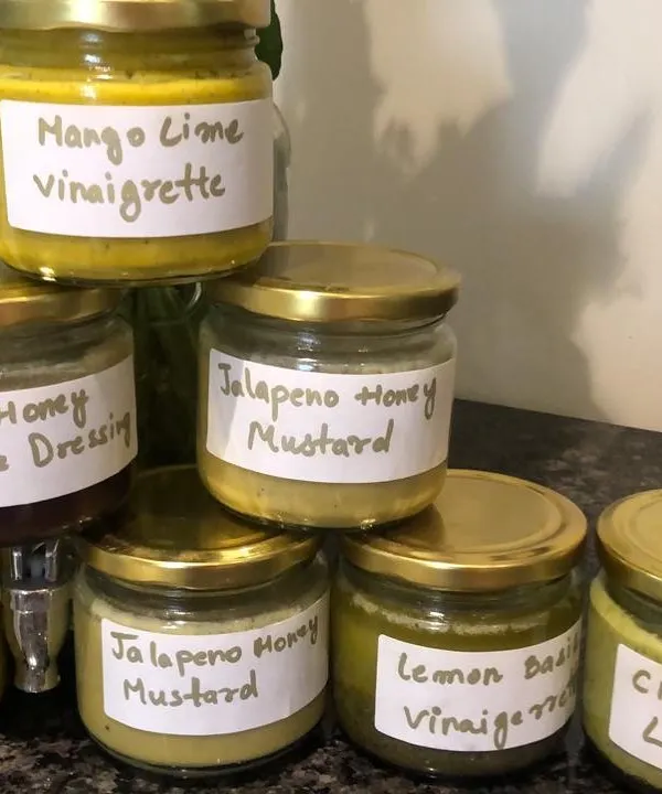 A selection of my homemade fresh salad dressings. You can see the variety, from Mango Lime Vinaigrette to Jalapeño Honey Mustard, all clearly labelled and ready to go.