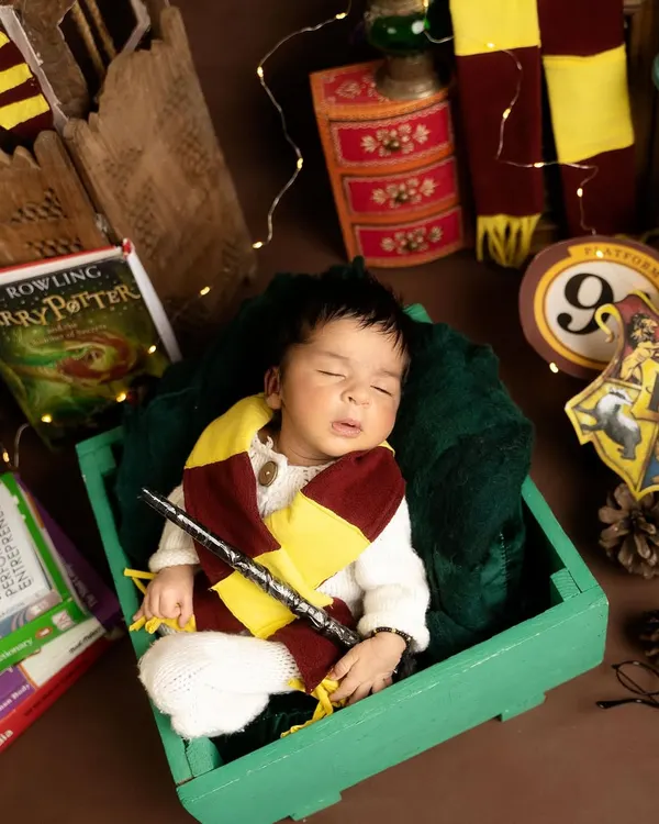 Ready for the Hogwarts Express! This little wizard is sleeping soundly with his magic wand, surrounded by props that bring the world of Harry Potter to life in this themed baby photoshoot.
