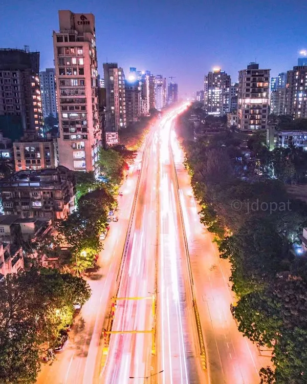 A long exposure shot from a drone, looking down a major road in Mumbai, turning the vehicle lights into brilliant white and red streaks.