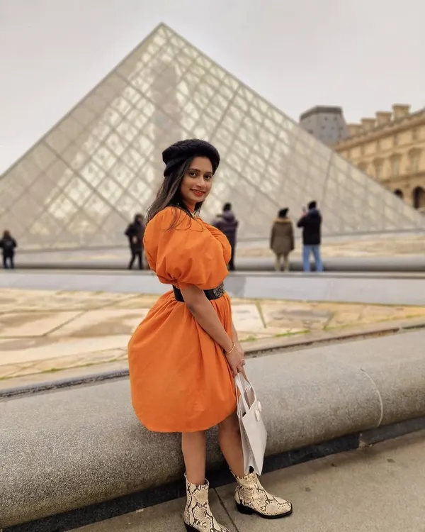 Our client looking absolutely radiant in our custom orange puff-sleeve dress while visiting the Louvre in Paris. We designed this dress to be both comfortable for exploring and stylish enough for a photoshoot.