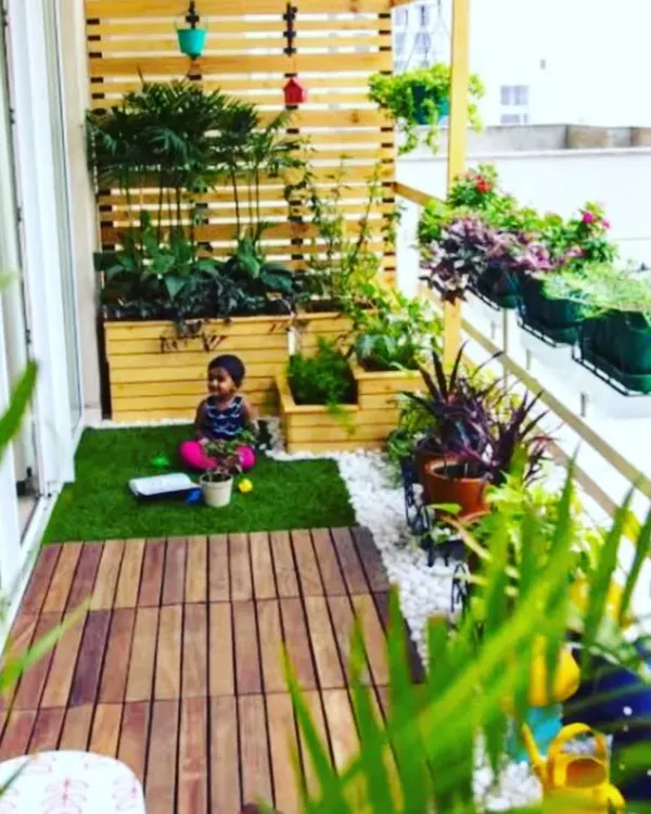 We transformed this apartment balcony into a safe and fun green space for the family. The design includes a mix of wooden decking and artificial grass, with raised planters and hanging pots to maximize the greenery.