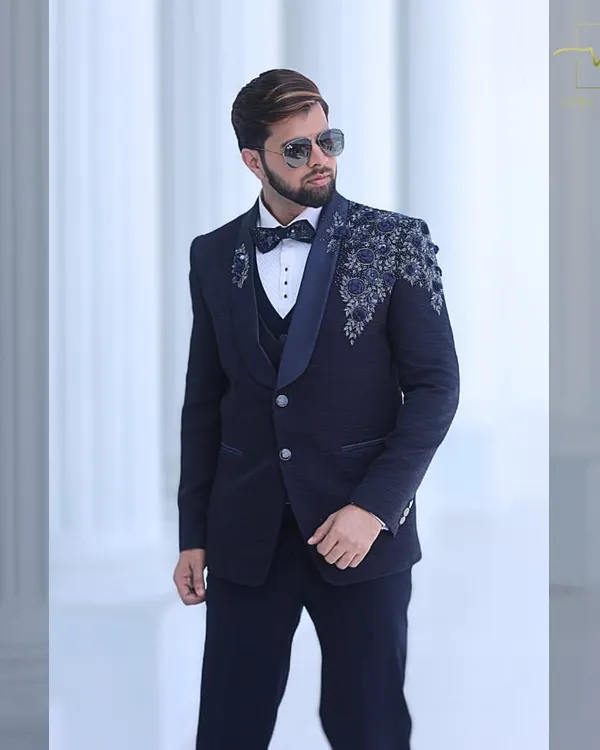 This is the hero item. A custom-tailored navy blue three-piece tuxedo, perfect for a groom's reception. The jacket features intricate floral sequin and beadwork on the shoulder and lapel, creating a look that is both modern and timeless.
