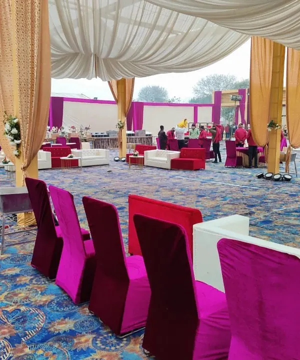 For large receptions, I provide comfortable lounge furniture. This setup includes plush white sofas and high-back chairs in pink and red velvet, arranged for conversation.