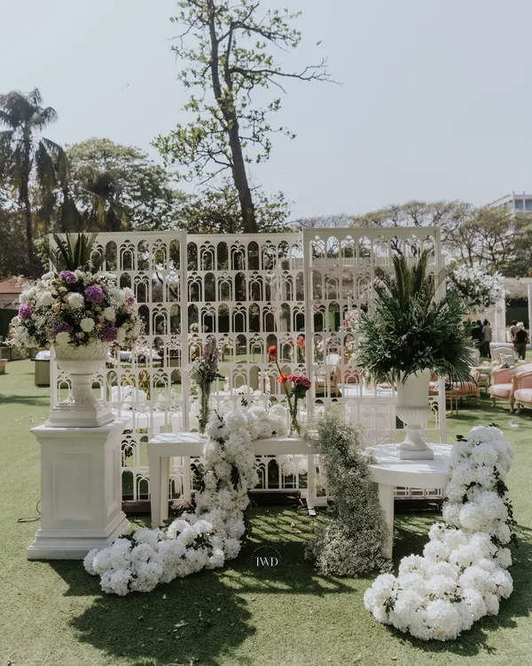 A beautiful photo corner created with white floral arrangements and intricate lattice screens. These details provided a perfect backdrop for guest photos at a vintage-themed wedding.