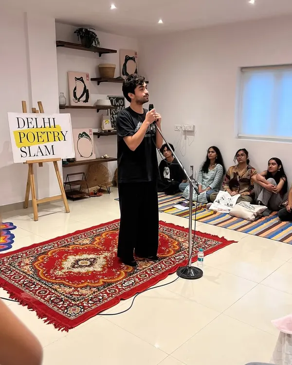 A poet takes the stage in our packed studio. We often have to pull out extra carpets to fit everyone, a testament to the incredible enthusiasm of the DelSlam fam.