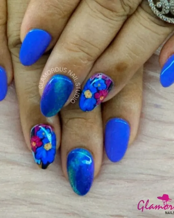 A stunning contrast of electric blue nails and intricate, hand-painted floral art. The accent nails feature a bouquet of pink and blue flowers, showcasing our detailed brushwork.
