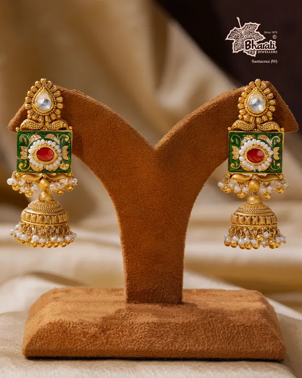 A tribute to India’s timeless artistry. These Meenakari jhumka earrings are hand-enameled with vibrant green and red floral motifs, framed in antique gold. The design is completed with a classic bell shape and delicate pearls.