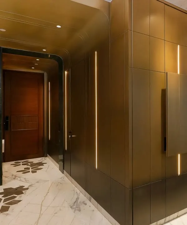 This view of the entryway shows the seamless integration of a concealed bar cabinet within the brass paneling. The design balances elegance and functionality, adding a layer of subtle intrigue.