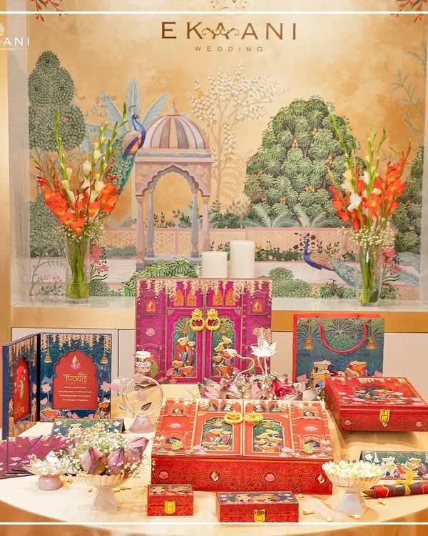 A complete wedding suite from my Pichwai-themed collection, set against a backdrop of heritage art. This display shows how I curate every element, from large hamper boxes to matching gift bags, to create a cohesive and opulent wedding story.