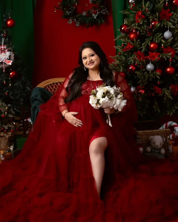 We can celebrate any season. This festive Christmas-themed maternity shoot uses a rich red gown and holiday decor to create a warm and magical portrait.
