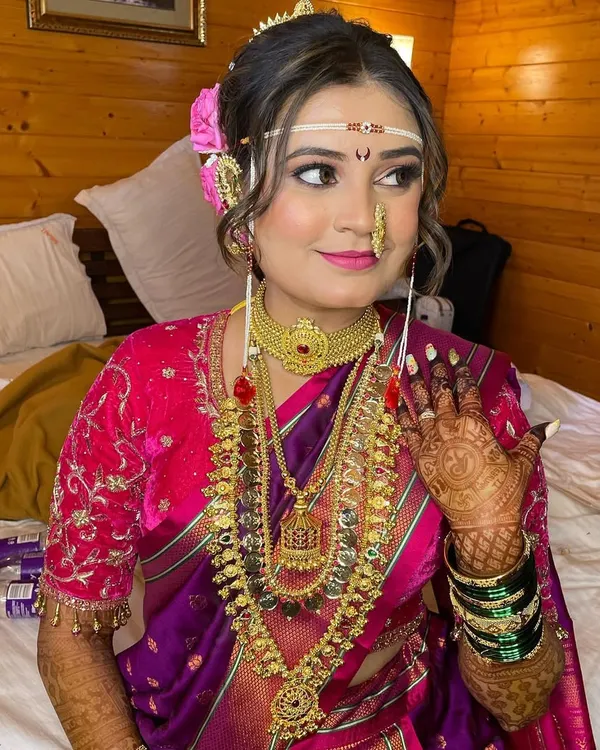 Representing tradition to ultimate perfection. This Maharashtrian bridal look features a classic 'mundavalya', a 'nath', and beautiful pink and purple tones in her makeup to match her Paithani saree.