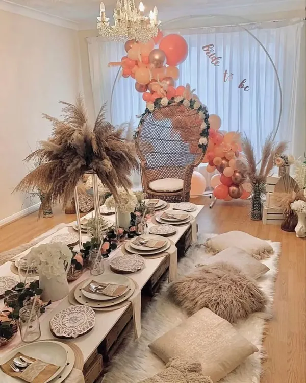 We love a boho bridal shower. For this event, we created a dreamy floor seating arrangement with low picnic tables, plush cushions, pampas grass, and a beautiful balloon arch for the bride-to-be's special peacock chair.