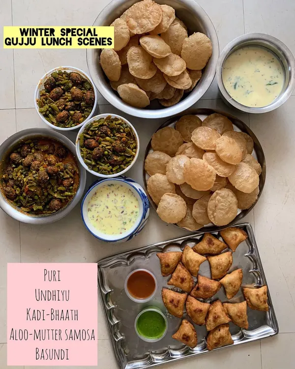 A winter special Gujju lunch scene. This comforting meal includes Puri, Undhiyu, Kadi-Bhaath, Aloo-Mutter Samosa, and Basundi for dessert.