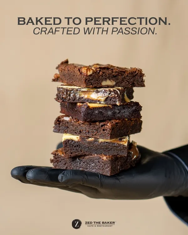 Baked to perfection, crafted with passion. A stack of my assorted brownies held in a gloved hand, showcasing the different textures and fillings I create.